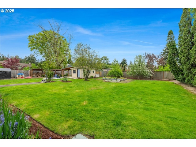 view of yard with a patio, a fenced backyard, and an outbuilding