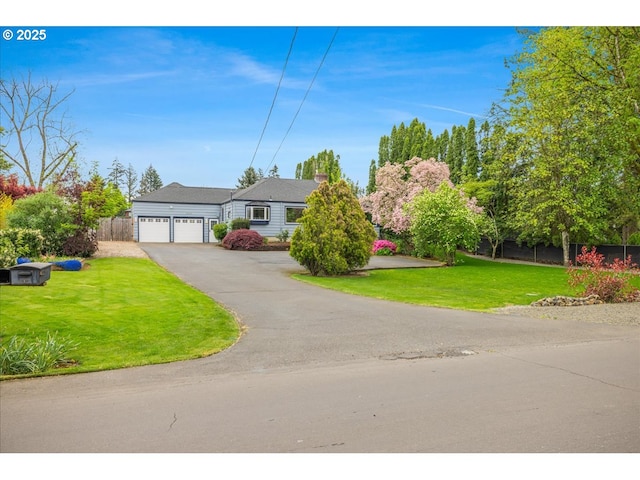 ranch-style home with fence, an attached garage, a front yard, and aphalt driveway