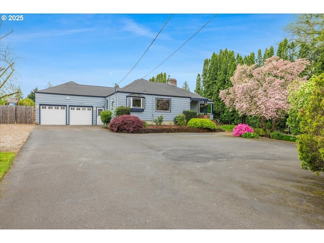 ranch-style house featuring an attached garage, fence, driveway, and a chimney