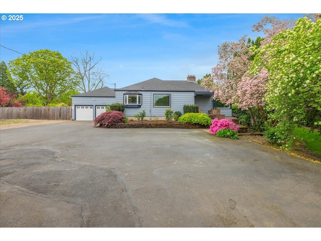 single story home with a garage, aphalt driveway, fence, and a chimney