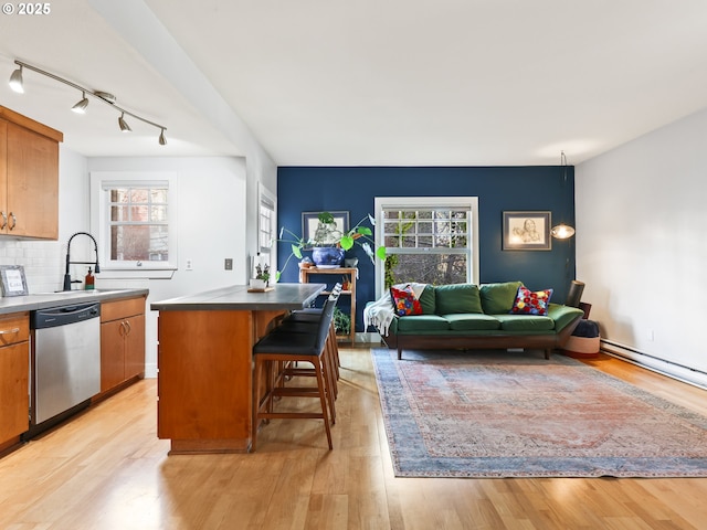 kitchen with dishwasher, sink, a wealth of natural light, a center island, and a breakfast bar