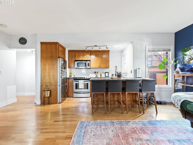 kitchen featuring light hardwood / wood-style flooring, tasteful backsplash, a breakfast bar, a kitchen island, and stainless steel appliances