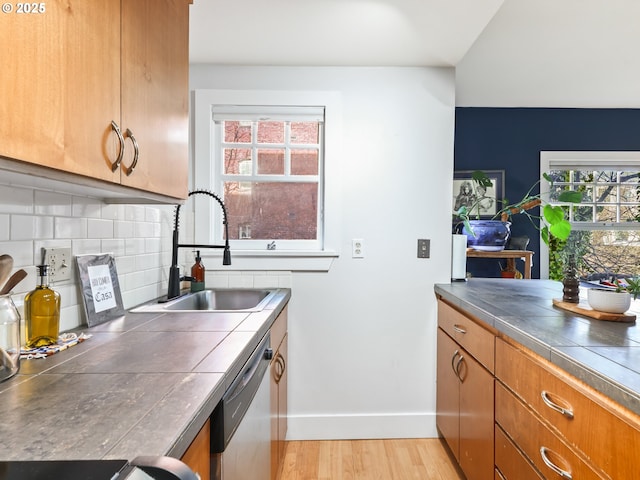 kitchen featuring tile counters, dishwasher, decorative backsplash, sink, and plenty of natural light