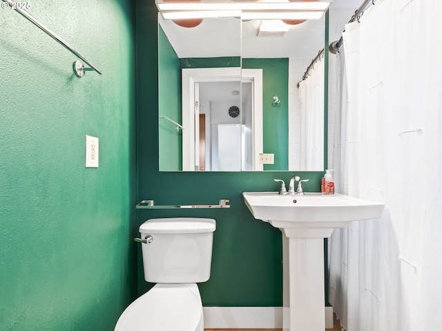 bathroom with curtained shower, toilet, and sink