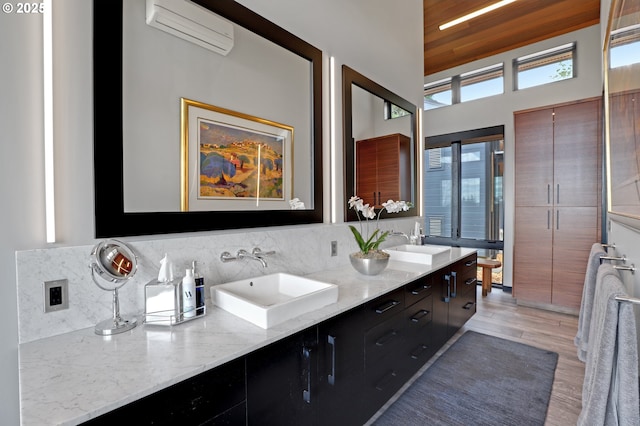 11440 NW Rock Creek Rd, Portland, OR 97231 - bathroom featuring a wall mounted AC, wood finished floors, double vanity, and tasteful backsplash