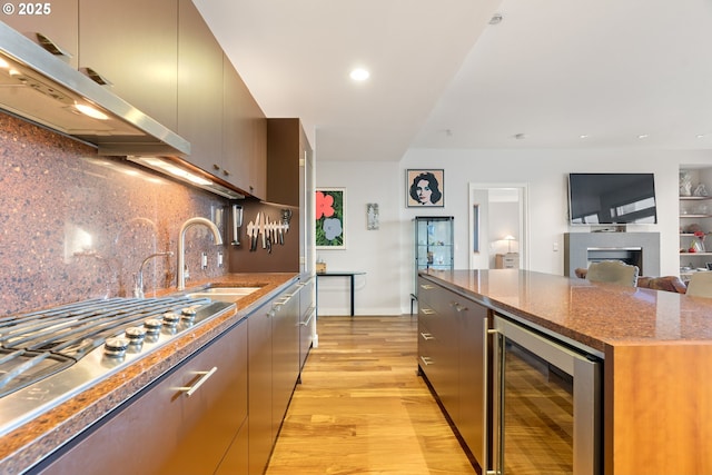 kitchen featuring backsplash, sink, light hardwood / wood-style floors, wine cooler, and stainless steel gas stovetop