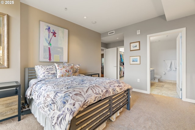 bedroom with light carpet, a walk in closet, ensuite bathroom, and a closet