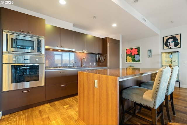 kitchen with a kitchen breakfast bar, decorative backsplash, dark stone countertops, a kitchen island, and stainless steel appliances