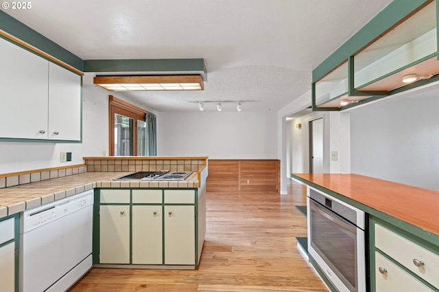 kitchen featuring a peninsula, electric cooktop, oven, light wood-style floors, and white dishwasher