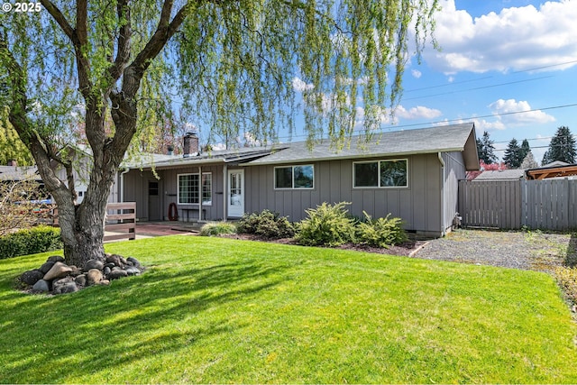view of front of property featuring a front lawn, board and batten siding, fence, and a chimney