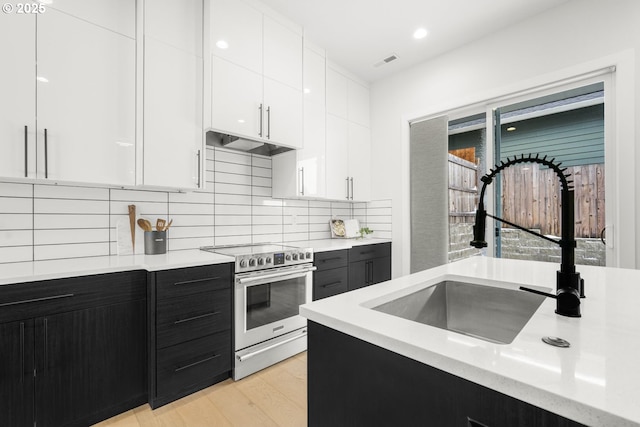 kitchen with sink, white cabinetry, tasteful backsplash, extractor fan, and stainless steel electric range oven