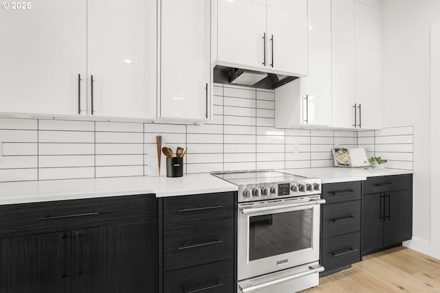 kitchen featuring white cabinetry, ventilation hood, light hardwood / wood-style flooring, electric stove, and backsplash