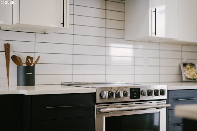 kitchen with stainless steel range with electric stovetop, backsplash, and white cabinets