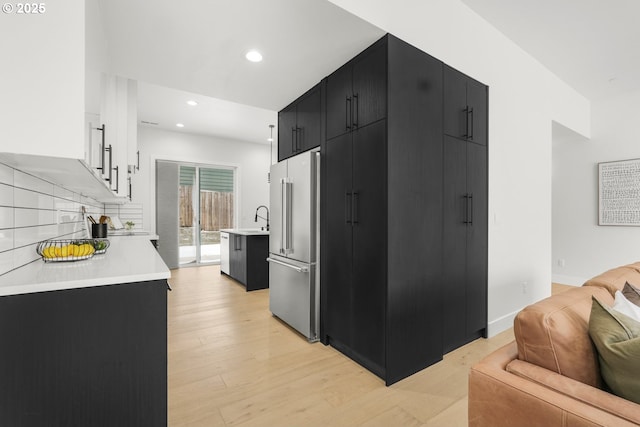 kitchen with sink, tasteful backsplash, light hardwood / wood-style floors, white cabinets, and high end refrigerator