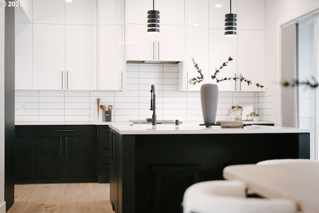 kitchen featuring sink, decorative light fixtures, decorative backsplash, and white cabinets