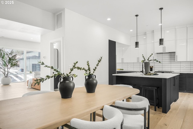 kitchen featuring backsplash, decorative light fixtures, a center island, and white cabinets