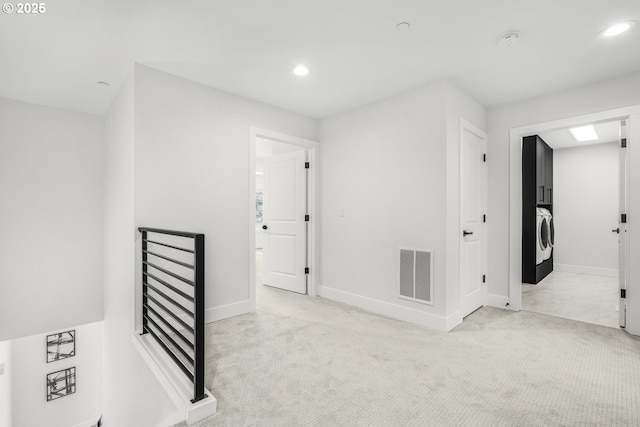 hallway with washer / clothes dryer and light carpet