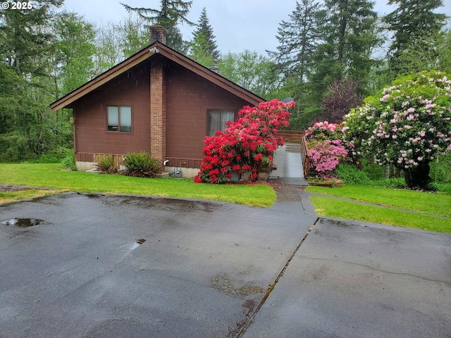 view of side of home with a yard, a garage, driveway, and a chimney