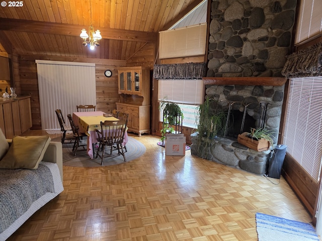 dining room featuring a stone fireplace, beam ceiling, wood walls, and a chandelier