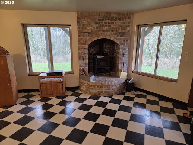 unfurnished living room with tile patterned floors, a wood stove, and baseboards