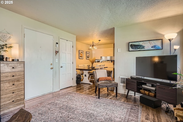 living area with visible vents, a notable chandelier, a textured ceiling, and wood finished floors