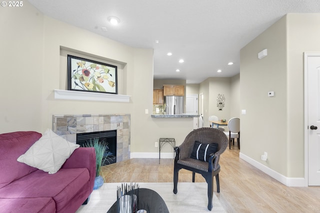 living room with a tiled fireplace and light wood-type flooring