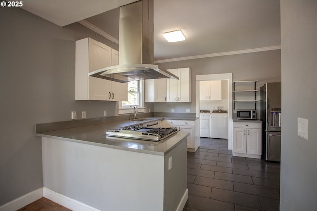 kitchen featuring washing machine and clothes dryer, stainless steel appliances, island exhaust hood, crown molding, and a sink