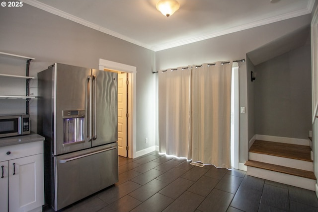 kitchen featuring stainless steel appliances, white cabinets, ornamental molding, and baseboards