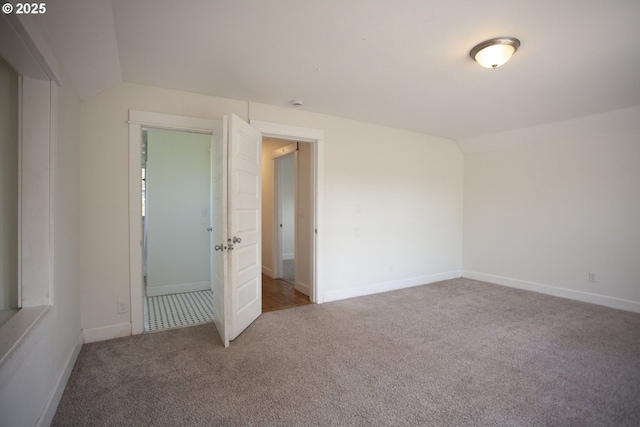 unfurnished bedroom with carpet floors, lofted ceiling, and baseboards