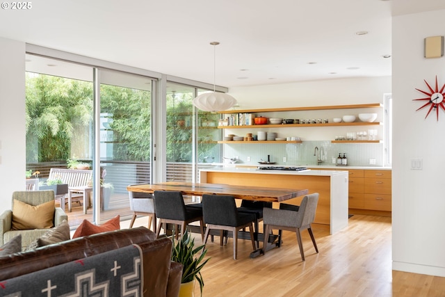 435 N Shaver St, Portland, OR 97227 - indoor wet bar with backsplash, gas stovetop, light wood-style flooring, decorative light fixtures, and a wall of windows