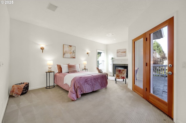 bedroom featuring light carpet, a fireplace with raised hearth, access to outside, and baseboards