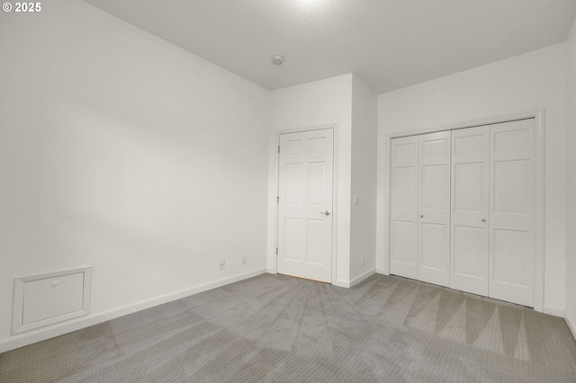 unfurnished bedroom with baseboards, a closet, and light colored carpet