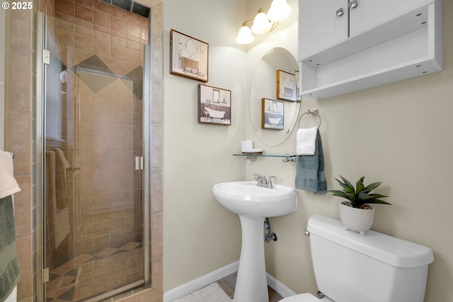 full bathroom with toilet, a stall shower, and baseboards