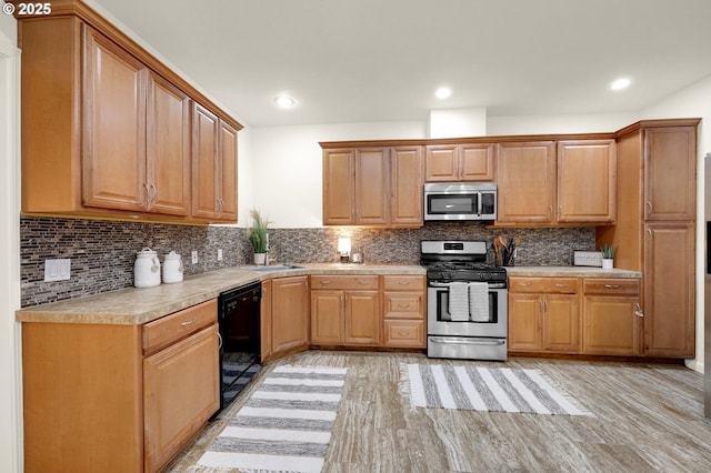 kitchen featuring appliances with stainless steel finishes, light wood-type flooring, light countertops, and backsplash