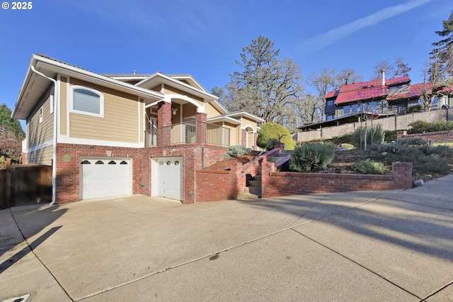 view of front of home with a garage, driveway, brick siding, and a balcony