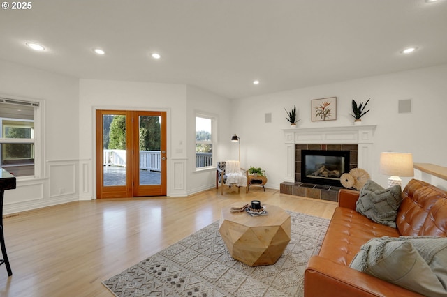 living area with light wood finished floors, a tile fireplace, visible vents, and a decorative wall