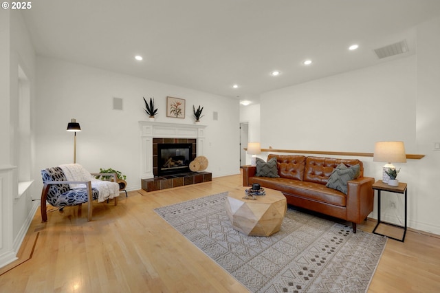 living room with light wood-style flooring, a fireplace, visible vents, and recessed lighting