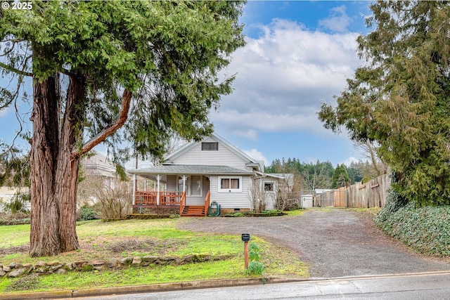 view of front of property featuring fence, driveway, a porch, a front lawn, and crawl space