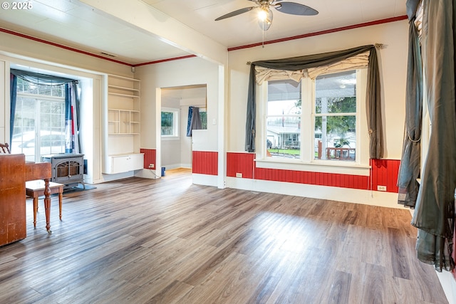 empty room featuring plenty of natural light, wood finished floors, and a wood stove