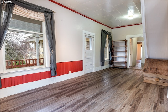 unfurnished room with ornamental molding, wood finished floors, and wainscoting