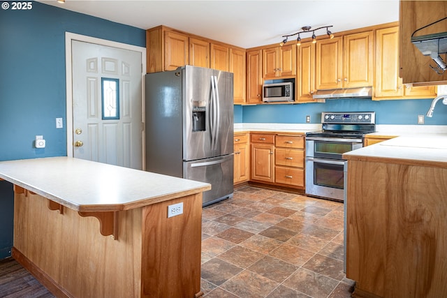 kitchen featuring extractor fan, appliances with stainless steel finishes, a peninsula, and light countertops