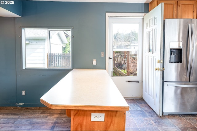 kitchen with a peninsula, stainless steel fridge with ice dispenser, brown cabinets, and light countertops