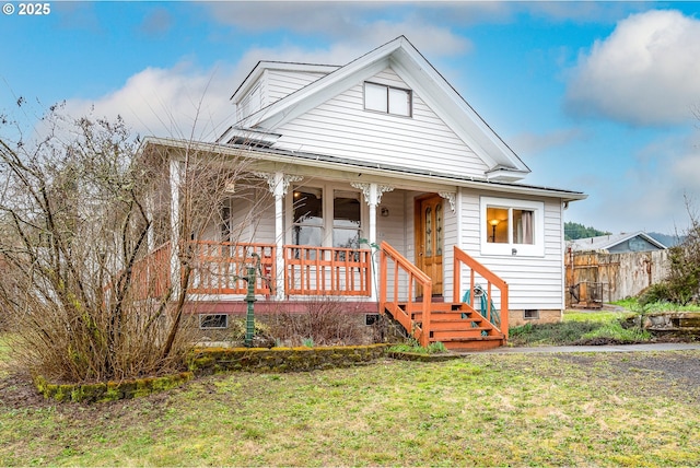 bungalow-style house featuring crawl space, a porch, a front yard, and fence