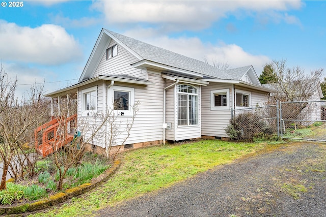 exterior space with fence, roof with shingles, a lawn, crawl space, and a gate