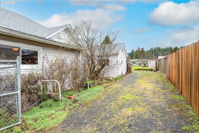 view of side of property featuring a shingled roof and fence