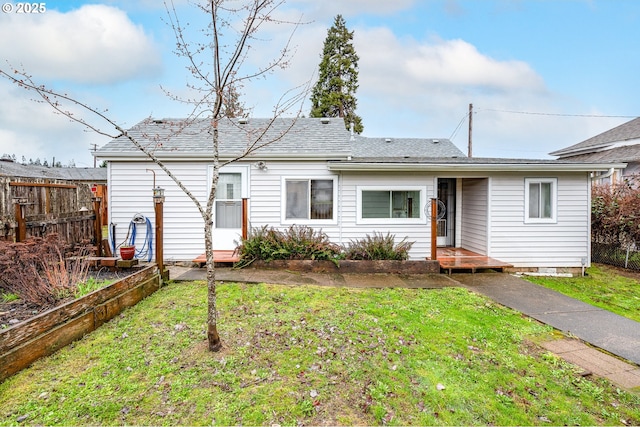 rear view of property with a lawn and fence