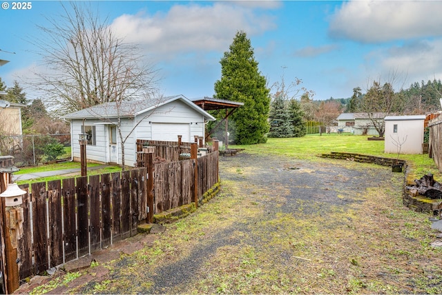 view of yard with an outdoor structure, fence, and a garage