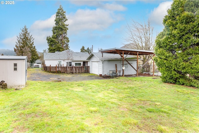 view of yard with an attached garage, an outdoor structure, and fence