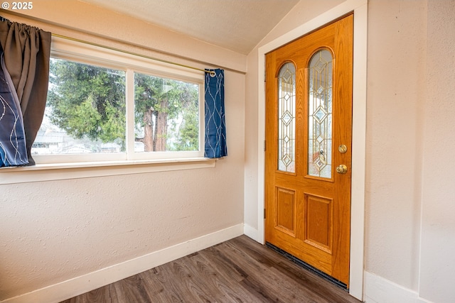 entryway with a textured wall, baseboards, wood finished floors, and vaulted ceiling