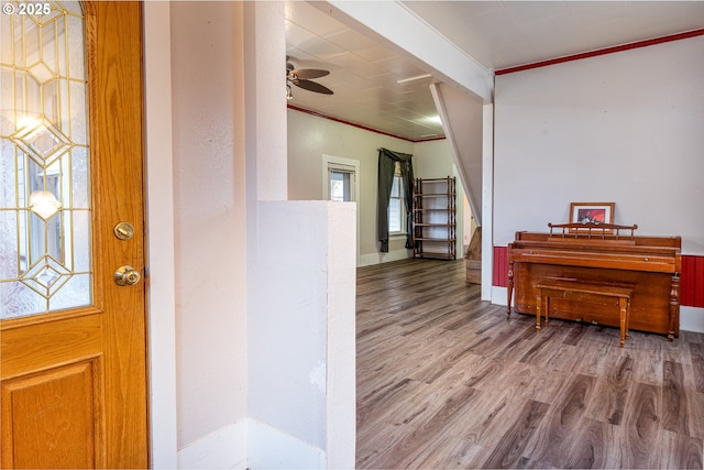 foyer entrance with ornamental molding, a ceiling fan, wood finished floors, stairway, and baseboards